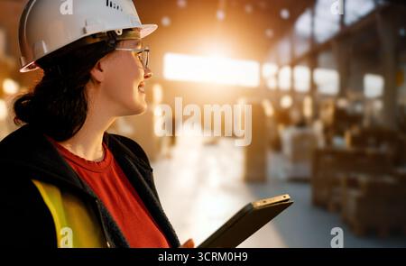 Une femme ingénieur industriel en casque blanc travaille dans un terminal à conteneurs. Banque D'Images