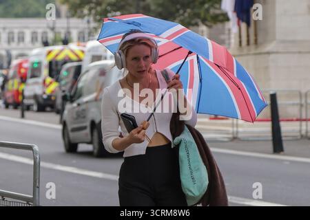 Londres. ROYAUME-UNI. 01 octobre 2025. Une femme s'abrite sous un parapluie de couleur Union Jack à Westminster, Londres, pendant de légères pluies. Selon le met Office, la tempête Amy devrait entraîner des vents allant jusqu'à 80 km/h et des avertissements de temps violent sont en place dans tout le Royaume-Uni. Credit : London News/Alamy Live News Banque D'Images