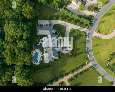 Vue aérienne d'un grand domaine avec une piscine, des pelouses bien entretenues et une allée circulaire, encadrée par des arbres luxuriants et des rues de banlieue, New Jersey, New Jersey, États-Unis. Banque D'Images