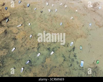 Vue aérienne de bateaux dispersés dans des eaux turquoises peu profondes révélant les fonds marins sablonneux en dessous, créant une mosaïque de textures naturelles, Cádiz, Andalousie, Espagne. Banque D'Images