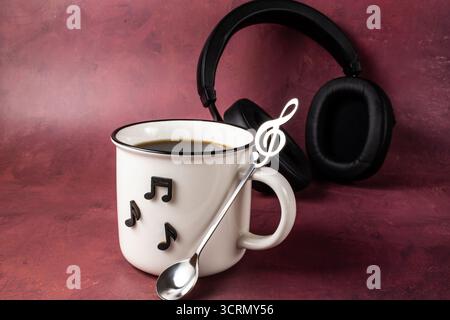Tasse de café avec écouteurs sur fond de couleur. Concept musical. Banque D'Images