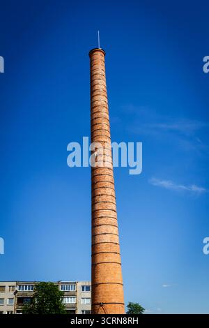 Vieille grande cheminée d'usine faite de briques contre le ciel bleu. Banque D'Images