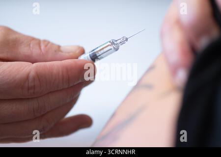 02 octobre 2025, Saxe, Dresde : un médecin tient une seringue préremplie avec un vaccin antigrippal lors d'un événement de presse à l'hôpital universitaire de Dresde pour la saison grippale 2025. Photo : Sebastian Kahnert/dpa Banque D'Images