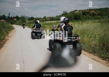 Amis en quad lors d'une aventure pittoresque sur la route de la campagne Banque D'Images