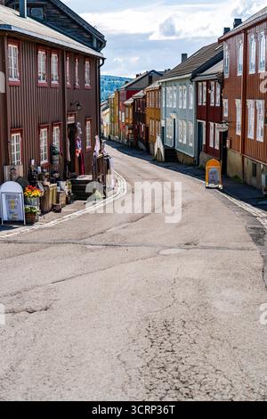 Les couleurs vives des bâtiments en bois bordent la rue vide de Røros, en Norvège, un site classé au patrimoine mondial de l'UNESCO, sous le soleil chaud d'une journée d'été Banque D'Images