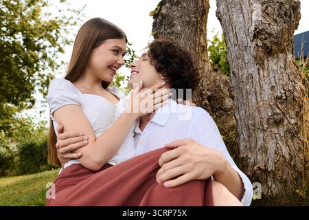 Un jeune couple partage un moment joyeux en plein air, souriant et embrassant dans un cadre magnifique. Banque D'Images