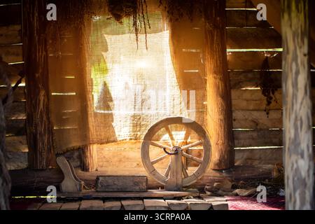 L'intérieur d'une ancienne cabane de village, avec une roue tournante et des bouquets d'herbes médicinales séchées dans le fond de la fenêtre, thym Banque D'Images