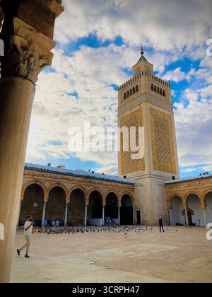 Cour de la mosquée Zitouna à Tunis, Tunisie - colonnades voûtées et minaret encadrés par une arche de pierre. Photographié le 24 septembre 2025. Banque D'Images