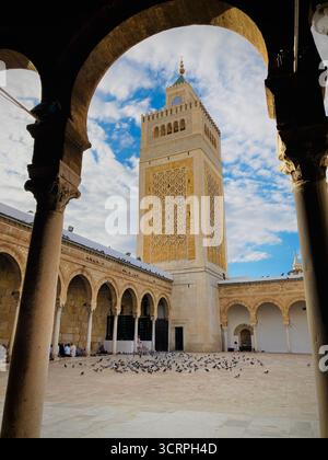 Cour de la mosquée Zitouna à Tunis, Tunisie - colonnades voûtées et minaret encadrés par une arche de pierre. Photographié le 24 septembre 2025. Banque D'Images