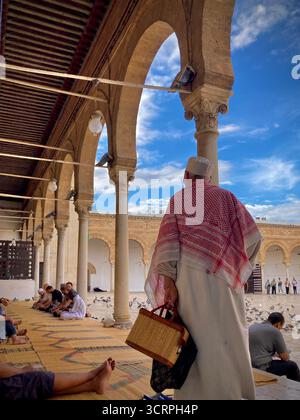 Cour de la mosquée Zitouna à Tunis, Tunisie - colonnades voûtées et minaret encadrés par une arche de pierre. Photographié le 24 septembre 2025. Banque D'Images