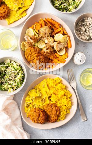 Dégustez un repas savoureux composé de riz garni d'œufs frits à la rhubarbe, de patates douces cuites au four et de légumes colorés. Salade fraîche et beignets de viande croustillants c Banque D'Images
