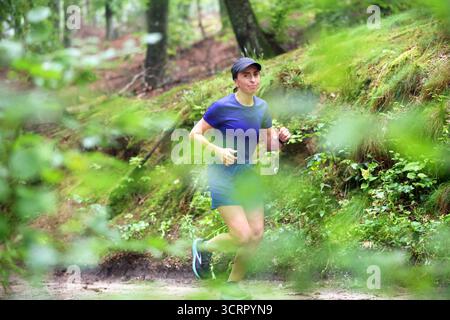 Sentier de femme courant à travers la forêt, exercice en plein air Banque D'Images