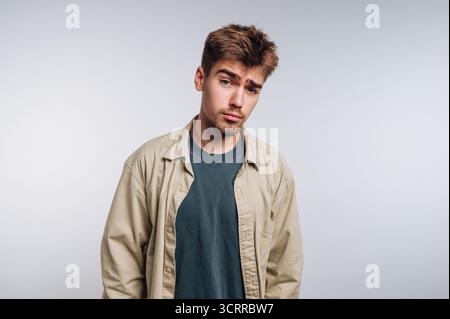 Jeune homme avec une expression sceptique, portant des vêtements décontractés. Banque D'Images