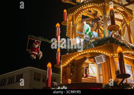 BÂLE, SUISSE – 8 DÉCEMBRE 2024 : une pyramide de Noël traditionnelle en bois ornée de personnages festifs, de bougies brillantes et d’un Santa Clau balançant Banque D'Images