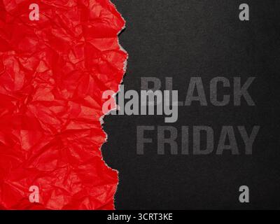 Un papier rouge froissé déchiré pour révéler un fond noir avec le texte « Black Friday ». Banque D'Images