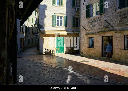 Sunny Old Town Street Corner avec des bâtiments historiques en pierre, des volets verts et une boutique piétonne entrant Banque D'Images