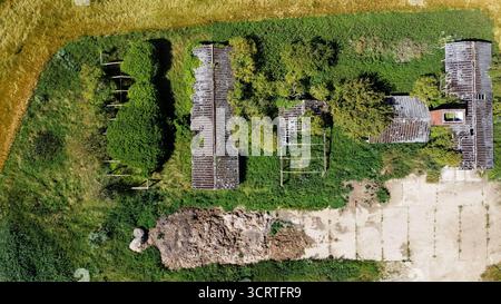 Vue aérienne des bâtiments agricoles abandonnés envahis par la végétation Banque D'Images