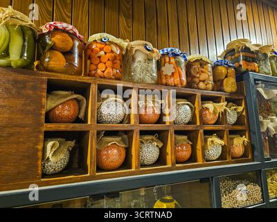 Étagère en bois rustique avec des bocaux en verre de légumes marinés, de légumineuses et de grains, stockés dans un style traditionnel. Bio fait maison. Banque D'Images