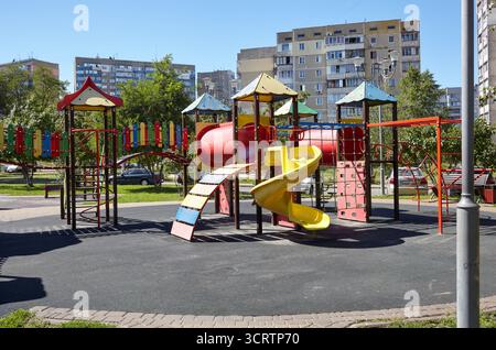 Aire de jeux colorée sur cour sans enfants à Kiev, Ukraine. Cour de jeu avec toboggan et autres éléments de terrain de jeu. Conce d'enfance de quartier urbain Banque D'Images