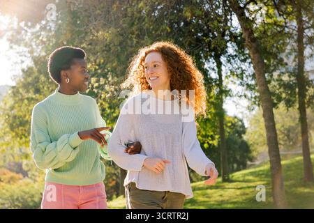 deux jeunes femmes souriant et parlant pendant une promenade Banque D'Images