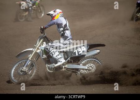 Pilote de motocross effectuer des virages sur piste poussiéreuse Banque D'Images