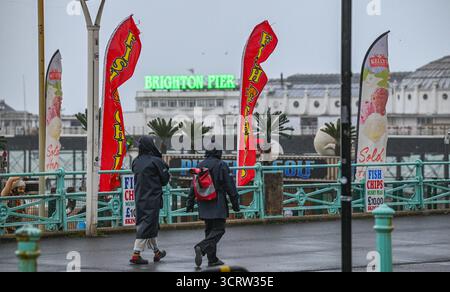 Brighton UK 3 octobre 2025 - marcheurs sur Brighton dans des vents forts alors que la tempête Amy approche avec les régions du nord-ouest de la Grande-Bretagne qui devraient être le plus touchées : crédit Simon Dack / Alamy Live News Banque D'Images