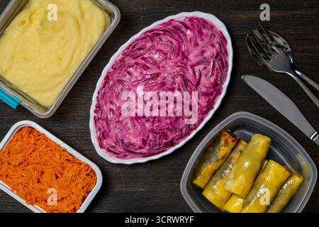 Plusieurs plats dans des boîtes en plastique pour le petit déjeuner sur une table en bois, gros plan, vue de dessus. Purée de pommes de terre, salade de betteraves avec mayonnaise, carottes râpées et w Banque D'Images
