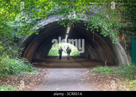 Deux personnes marchant en silhouette à travers un tunnel Banque D'Images