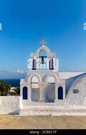 Santorin Grèce. Oia. Une église classique de style architectural des Cyclades avec un clocher et des fenêtres cintrées se dresse contre un ciel bleu clair Banque D'Images
