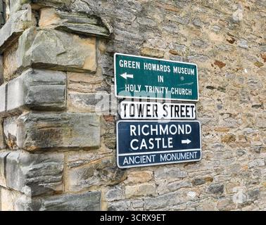 Panneaux indiquant le Green Howards Museum et le château de Richmond sur un mur de pierre dans Tower Street, Richmond, North Yorkshire, Angleterre, Royaume-Uni Banque D'Images