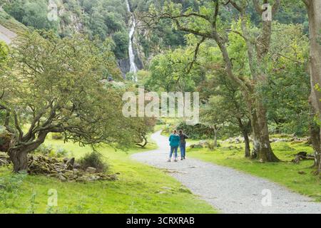 Deux randonneuses debout sur un sentier regardant les chutes d'Aber, Rhaeadr Fawr au loin, vêtues de matériel de randonnée Banque D'Images