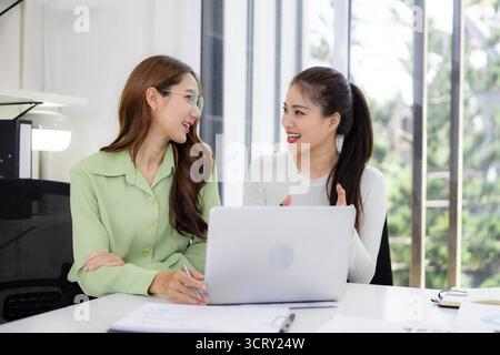Deux femmes professionnelles asiatiques discutent volontiers des idées Partager des pensées travailler ensemble cadre de bureau contemporain lumineux utilisant la technologie d'ordinateur portable Banque D'Images