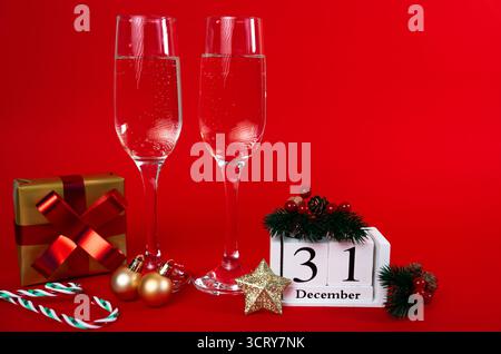 Deux verres à champagne avec cadeaux, ornements et calendrier montrant le 31 décembre. Célébration de la Saint-Sylvestre. Banque D'Images