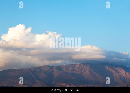 Montagnes dans une vallée au coucher du soleil sur un fond de ciel bleu avec des nuages blancs Banque D'Images