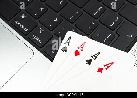 Gros plan de cartes à jouer sur un clavier d'ordinateur portable, avec as et King of Spades suggérant un flush royal dans le poker la scène implique technol Banque D'Images