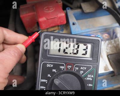 Vérification des niveaux de tension de la batterie sèche. Commande de charge de batterie de véhicule ou d'automobile avec voltmètre numérique. Banque D'Images