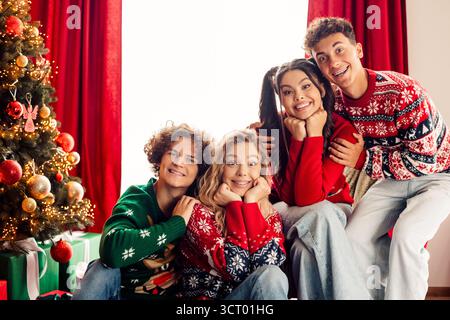Adolescents joyeux célébrant Noël ensemble à la maison avec des pulls et des décorations colorés, capturant le bonheur festif et l'amitié Banque D'Images