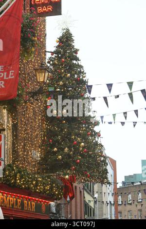 Dublin, Irlande - 03 octobre 2025 - Un grand arbre de Noël avec des décorations se lève tôt sur le côté du pub Temple Bar dans le centre-ville de Dublin par un après-midi humide début octobre Banque D'Images