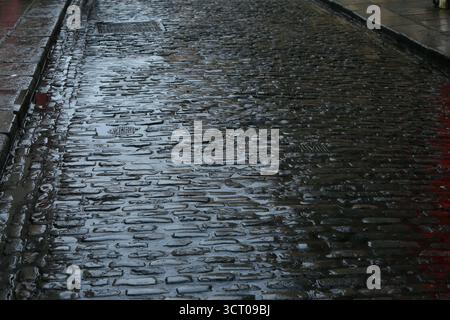 Dublin, Irlande - 03 octobre 2025 - la lumière brille sur des pavés humides sombres sur une surface de route à Temple Bar dans le centre-ville de Dublin par une journée humide et venteuse alors que la tempête Amy approche dans la capitale irlandaise Banque D'Images