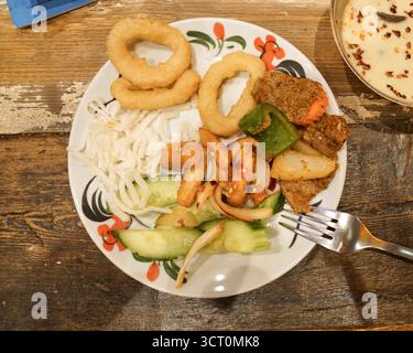 Délicieuse assiette de nourriture avec des collations frites, des légumes et de la viande servis sur un plat coloré dans un cadre confortable Banque D'Images