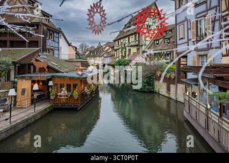COLMAR, FRANCE – 11 DÉCEMBRE 2024 : des décorations festives de Noël ornent les bâtiments historiques à colombages et le canal dans la pittoresque petite Venic Banque D'Images