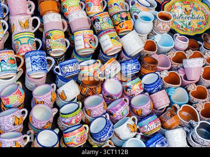 Une table pleine de diverses tasses et bols colorés avec le mot 'bienvenido' écrit dessus. Les tasses et les bols sont disposés de manière à ce qu'ils soient tous Banque D'Images