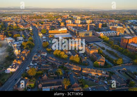 Vue aérienne matinale de Chester, Royaume-Uni, mettant en évidence le canal traversant la ville, une grande cheminée historique, des entrepôts et des logements en briques rouges. Banque D'Images
