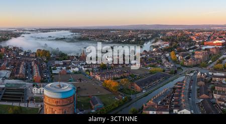 Vue aérienne panoramique de Chester au lever du soleil avec la brume roulant sur les champs et les toits. Banque D'Images