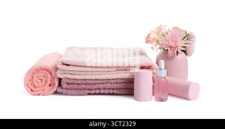 Pile de serviettes éponge fraîches, de produits cosmétiques et de fleurs isolées sur blanc Banque D'Images