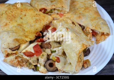Une assiette de sandwich Pizza rempli de poulet avec des morceaux de tomate, poivre, olive, fromage mozzarella, sauce tomate dans un sandwich Banque D'Images