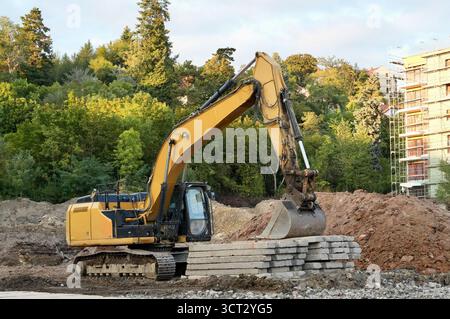 excavatrice sur un chantier de construction sur un fond d'arbres verts Banque D'Images