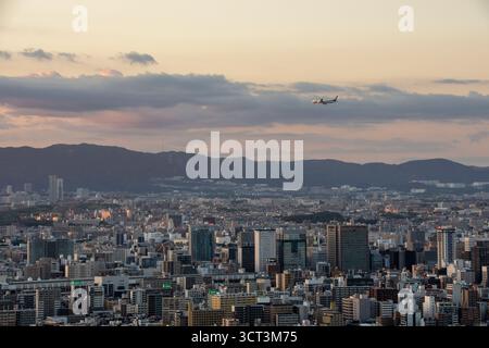 Avion survolant Osaka au coucher du soleil, Japon Banque D'Images