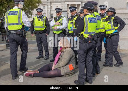 Londres, Royaume-Uni. 4 octobre 2025. Un groupe de policiers entoure un manifestant assis dans un espace public urbain, peut-être près d'un monument gouvernemental ou civique. Les policiers portent des gilets de haute visibilité portant la mention « POLICE » et semblent surveiller la personne ou interagir avec elle. Défendre nos jurys organisent une manifestation non violente à Trafalgar Square. La manifestation vise à lever l'interdiction de Palestine action, qui a été interdite en tant que groupe terroriste en juillet 2025 en vertu de la loi britannique de 2000 sur le terrorisme. Penelope Barritt/Alamy Live News Banque D'Images