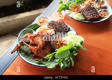 Ayam Goreng Rempah, poulet frit aux épices assaisonnées et savoureuses. Servi avec riz et Lalapan Banque D'Images